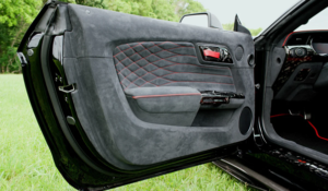 Upgraded Mustang interior door panel featuring Alcantara, red diamond stitching, and carbon fiber accents.